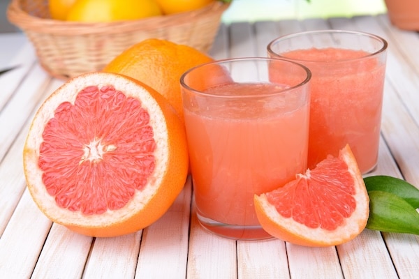 Ripe grapefruit with juice on table close-up